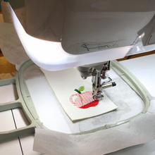 Load image into Gallery viewer, Apple keyfob being stitched in the hoop