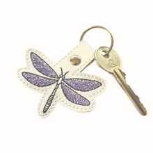 Load image into Gallery viewer, Dragonfly keyfob stitched with purple and black thread on to white faux leather and finished with a chrome metal rivet and split ring with key