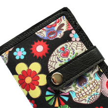 Load image into Gallery viewer, Close up of a skull patterned fabric notebook book stitched on black faux leather with a tab and rivet fastener