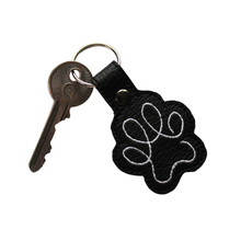Load image into Gallery viewer, Paw print keyring in black faux leather with white stitching and key attached
