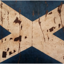 Load image into Gallery viewer, Close up view of the Scottish Flag cross in a mottled beige colour with dark brown 'splashes' on a navy velvet background