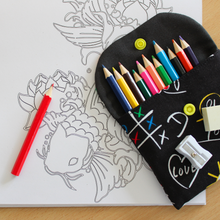 Load image into Gallery viewer, Coloured pencils in a black 'Scribble' fabric pencil case on a colouring in pad
