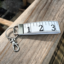 Load image into Gallery viewer, Tape measure keyfob with lobster clasp on a wooden handrail