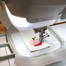 Load image into Gallery viewer, Apple keyfob being stitched in the hoop
