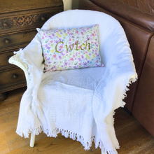 Load image into Gallery viewer, Cwtch cushion stitched in green on floral fabric on a chair with a white throw
