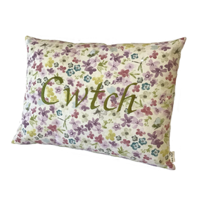 Cwtch cushion stitched in green on floral fabric viewed from the right side