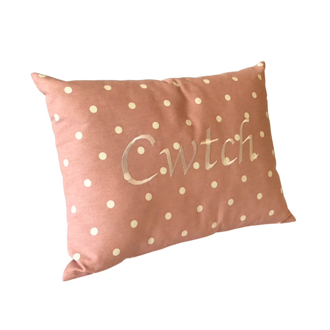 Cwtch cushion on pink fabric with white spots