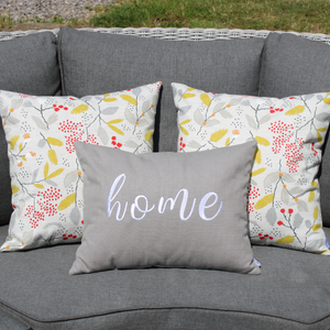 Embroidered Home cushion on soaf with two floral cushions behind