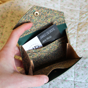 A green vine cork purse opened to show the credit card inserts, receipt pocket and central area for coins