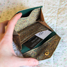 Load image into Gallery viewer, A green vine cork purse opened to show the green faux leather lining with a receipt pocket and central area for coins
