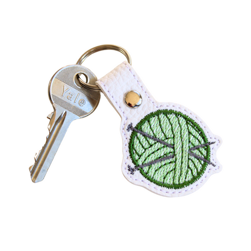 Knitting keyfob with green yarn and a key attached