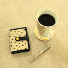 Load image into Gallery viewer, Bumblebee notebook on a coffee table with a silver pen and a cup
