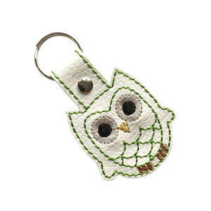 Owl keyfob with green outline stitching on white faux leather finished with a metal rivet and split ring