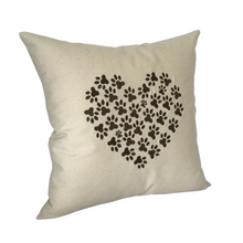 Load image into Gallery viewer, Cushion with pawprints embroidered in a heart shape on to a neutral cotton background fabric viewed from the left side angle
