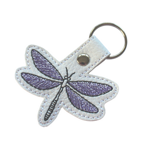 Dragonfly keyfob stitched in purple and black threads on to white faux leather with chrome metal rivet and split ring
