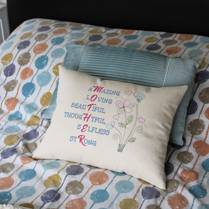 Mother Word Collage cushion on a bed with spotty bed linen in front of a blue cushion
