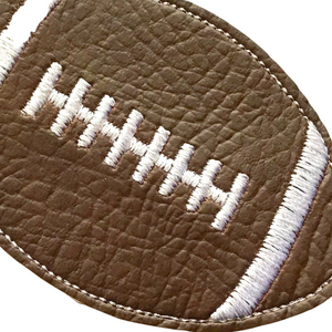 Close up of a rugby ball keyfob with white stitching on brown faux leather
