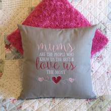 Load image into Gallery viewer, Mums Love Us the most embroidered cushion text stitched in white, light pink and dark pink on grey fabric on a sofa in front of a pink cushion
