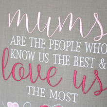 Load image into Gallery viewer, Close up view of the embroidered stitching of the Mums Love Us the most embroidered cushion text stitched in white, light pink and dark pink on grey fabric
